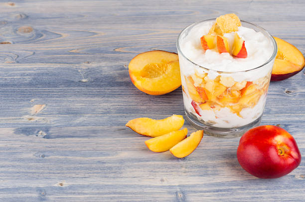 Colorful healthy breakfast with corn flakes, ripe slice peach on blue wood board. Decorative border with copy space.