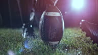 istock SLO MO American football player kicking the ball held by his teammate on the field at night 700660470