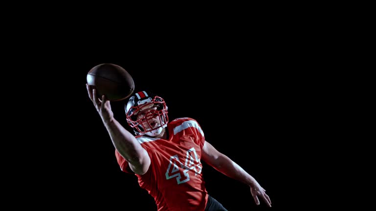 SPEED RAMP American football player in red jersey catching the ball with one hand on black background