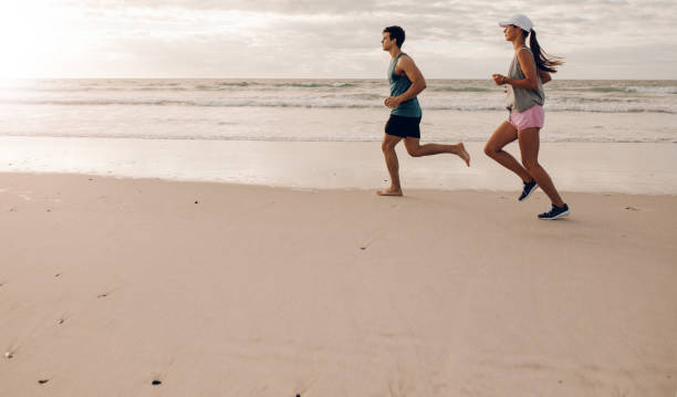 istock Young couple on running along the shore 700664412