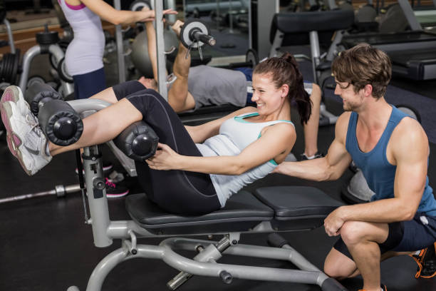 istock Trainer man helping woman doing her crunches 700672346