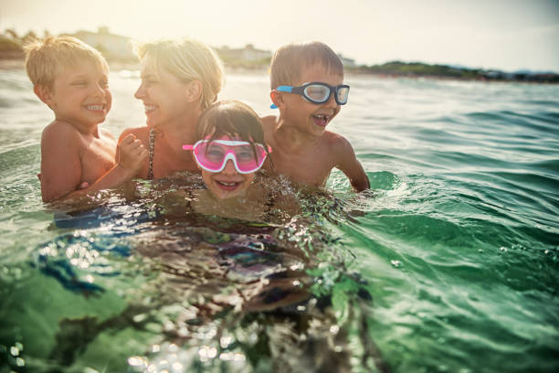 istock Mother with three kids splashing in sea waves 700673058