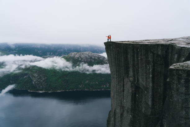 paar steht auf dem preikestolen in norwegen - lysefjord stock-fotos und bilder