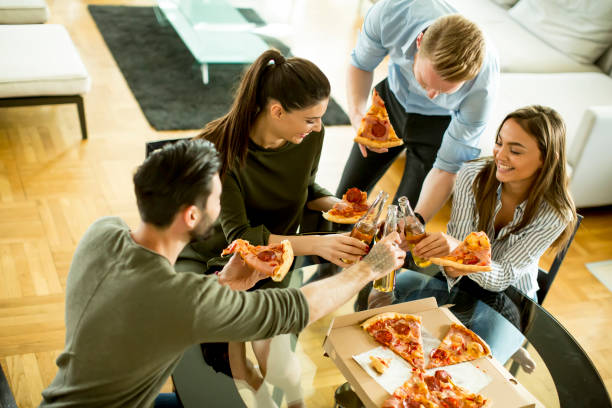 istock Young people eating pizza and drinking cider in the modern interior 700684856