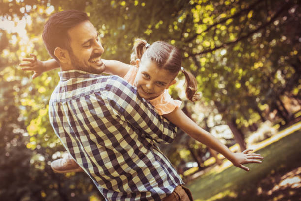 istock Father holding his daughter in his arms and looking at camera. 700688522