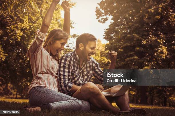 Young Couple Sitting On The Grass Happy Couple Using Laptop Stock Photo - Download Image Now