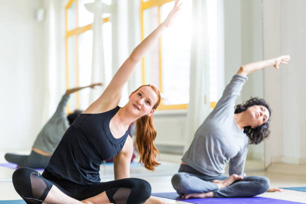 istock Women stretching on the floor at yoga class 700717978