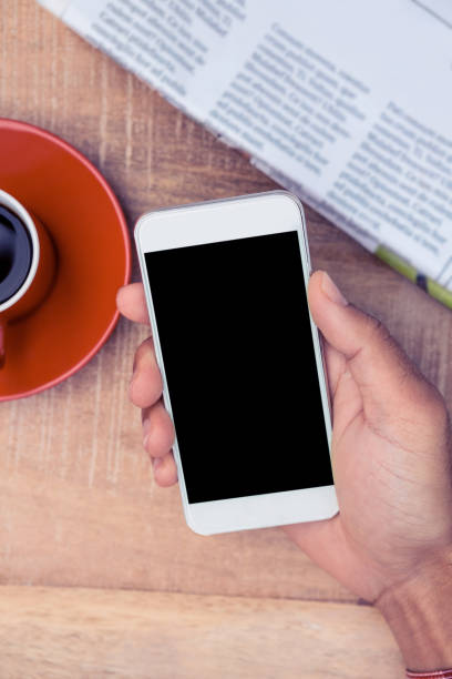istock Person using smart phone by coffee and newspaper on table 700719022
