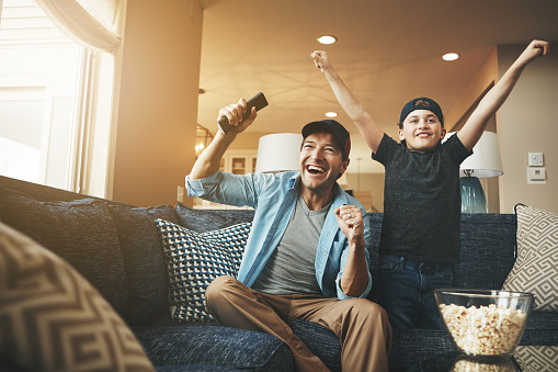 Shot of an enthusiastic father and son watching a sports match on tv at home