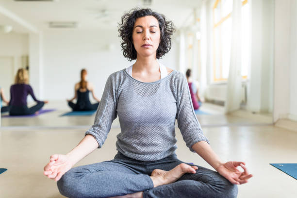 istock Mature woman meditating in gym class 700721880