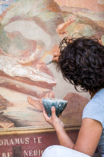 restorer working on antique outdoor chapel fresco in italy: applying stucco plaster - restoring art painting artist imagens e fotografias de stock