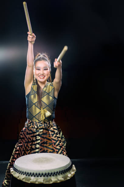 hermosa asiática drummer girl con baquetas, estudio tiro sobre un fondo oscuro. copia espacio. - taiko drum fotografías e imágenes de stock