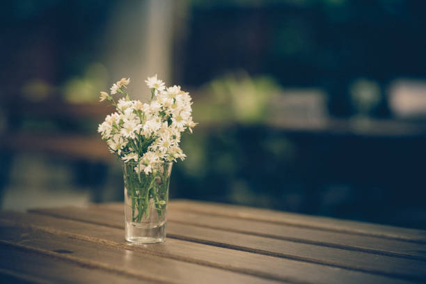 istock White flower on the wood table ; vintage colour tone 700726186