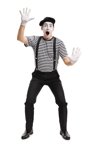 Full length portrait of a mime holding his hands on an invisible wall isolated on white background