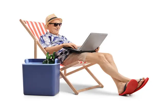 Photo of Tourist with laptop in deck chair next to cooling box