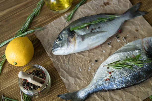 istock Raw fish cooking and ingredients. Dorado, lemon, herbs and spices. 700750584