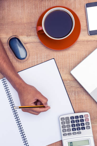 istock Businessman writing on notebook by coffee at desk 700769758