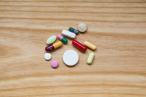 Lot of colorful pills on a wooden table. Different shapes and sizes