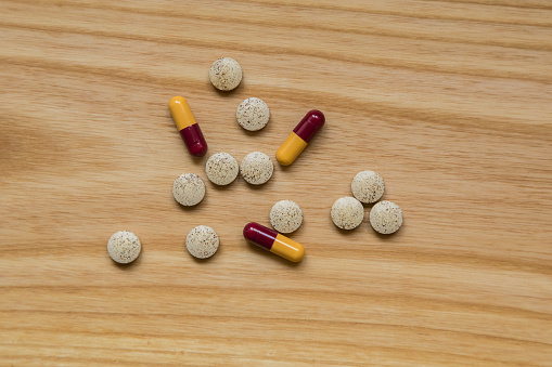 Lot of colorful pills on a wooden table. Different shapes and sizes