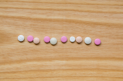 Lot of colorful pills on a wooden table. Different shapes and sizes