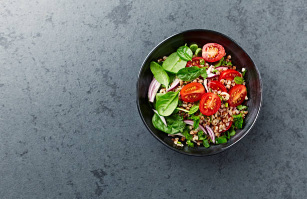 Buckwheat salad with cherry tomatoes and baby spinach stock photo