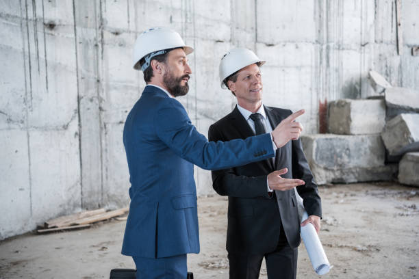 istock Two professional mature architects with blueprint working at construction site 700788306