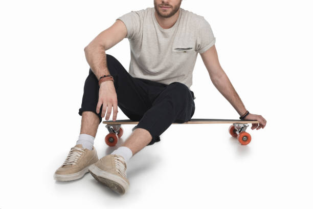 istock young man wearing black jeans, sitting on longboard, isolated on white 700794704