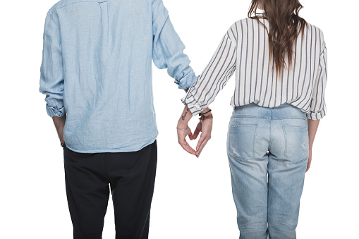 Back view of young couple holding hands in shape of heart symbol