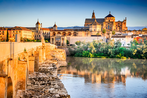 Cordoba, Spain. Roman Bridge on Guadalquivir river and The Great Mosque (Mezquita Cathedral) at twilight in the city of Cordoba, Andalusia.