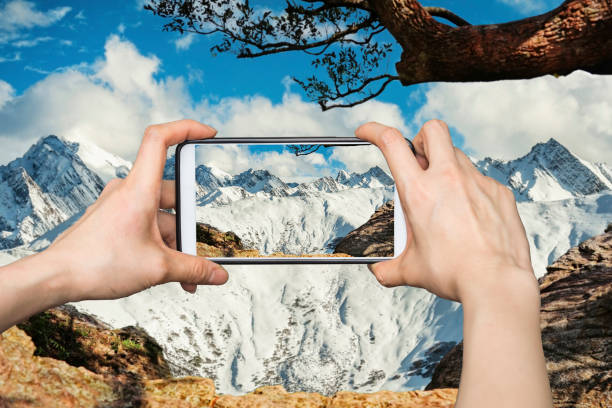 istock Girl taking pictures on mobile smart phone in High snow mountain in China 700801708