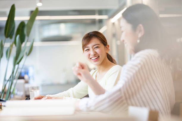オフィスで会話をする女性たち - 日本人　笑顔 ストックフォトと画像