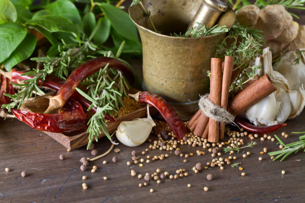 Different herbs and spices on a wooden table . Old copper mortar with spices .