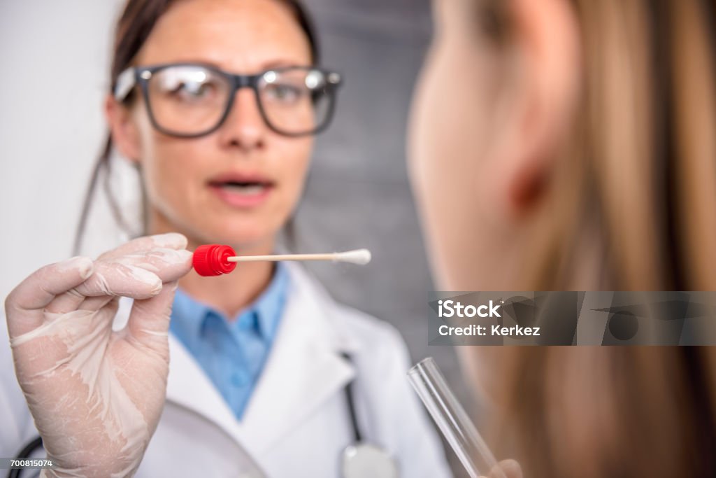 Female doctor taking a throat culture Female pediatrician using a swab to take a sample from a patient's throat Cotton Swab Stock Photo