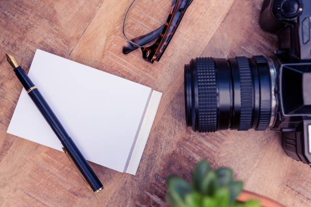 istock Camera by pen and paper on wooden table 700817236