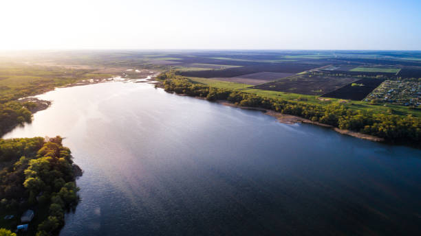 istock Aerial: Flying over a lake with sun illuminating the water. 700833284