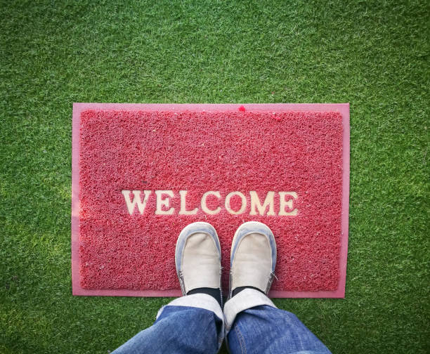 istock Feet on Welcome Red Mat on green grass .