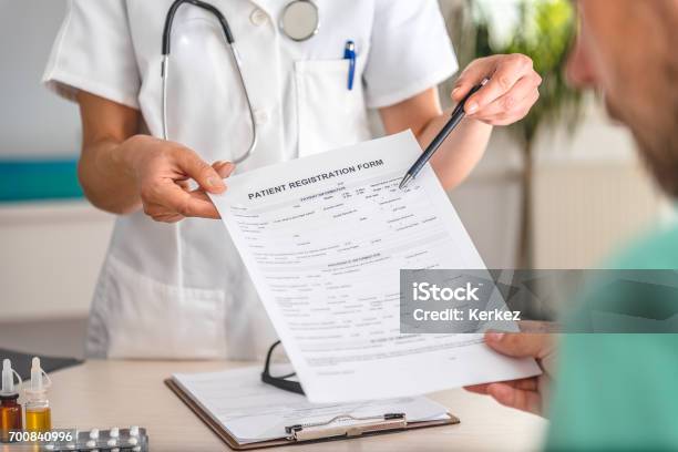 Médico Recibe Formulario Registro De Pacientes Foto de stock y más banco de imágenes de Paciente - Paciente, Registro, Firmar