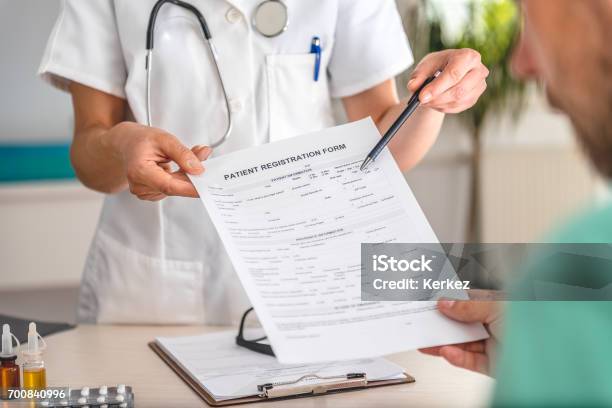 Doctor Receiving Patient Registration Form Stock Photo - Download Image Now - Patient, Registration Form, Signing