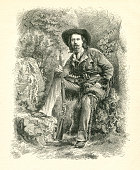 istock Buffalo Bill sitting with rifle in forest wild west 1877 700865750