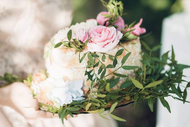 istock bride holding wedding cake. wedding cake decorated with flowers 700867104