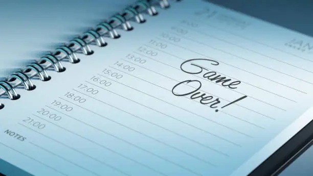 Closeup of a personal calendar setting an important date representing a time schedule. The words Game over written on a white notebook to remind you an important appointment.