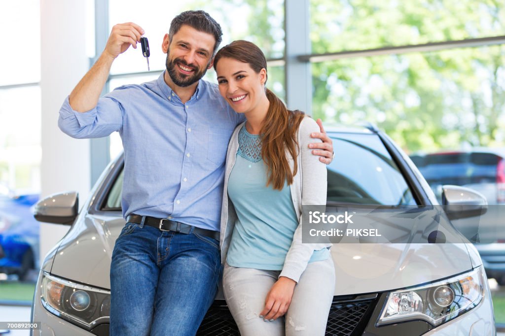 Young couple buying a car Young couple in the showroom, choosing a car Car Stock Photo