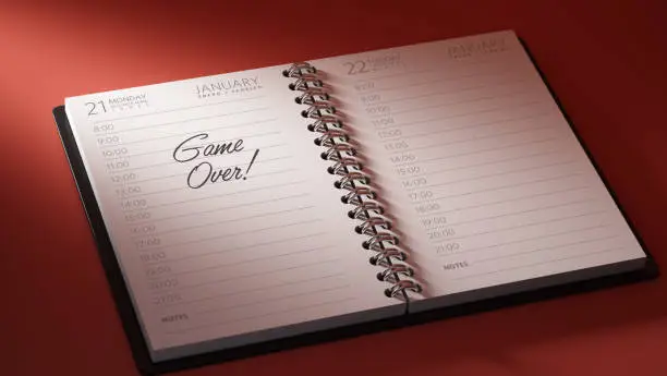 Closeup of a personal calendar setting an important date representing a time schedule. The words Game over written on a white notebook to remind you an important appointment.