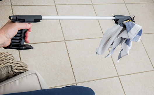 Patient or disabled person using a grabber / reacher to pick up a tea towel