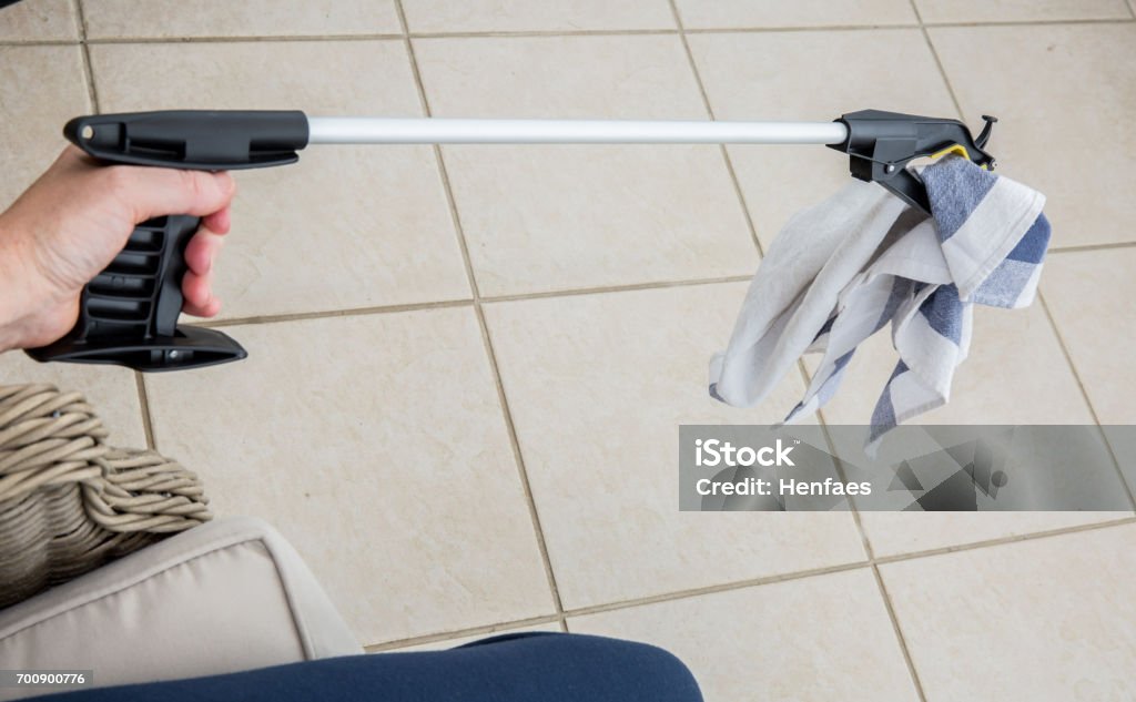 Patient or disabled person using a grabber / reacher Patient or disabled person using a grabber / reacher to pick up a tea towel Grabber Tool Stock Photo