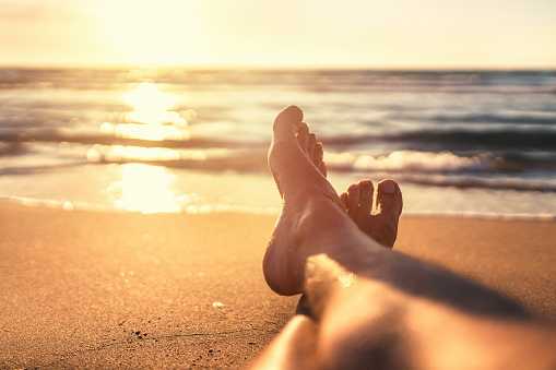 Woman wearing stylish flip flops resting on sandy beach and enjoying beautiful seascape, closeup