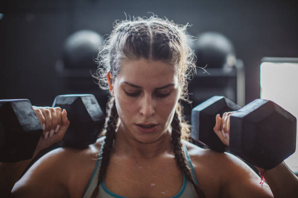 Gritty Women Woman weightlifting with dumbbells in gym weightlifting photos stock pictures, royalty-free photos & images