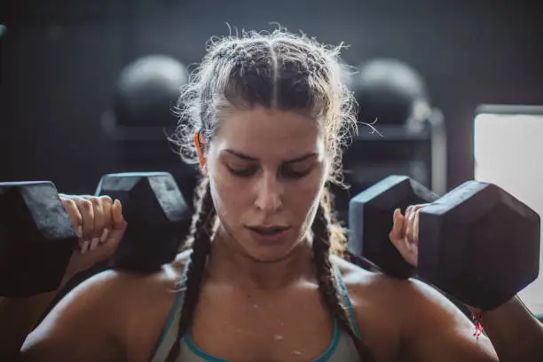 Woman weightlifting with dumbbells in gym