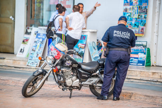 Cozumel, Mexico - December 29, 2017: Policeman on motorcycle on Cozumel street with few people talking on background
