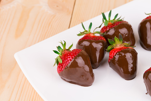 Strawberries in chocolate. Located on the wooden background.